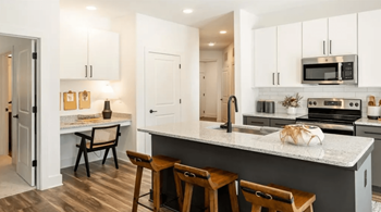 A kitchen with white cabinets and a marble countertop.